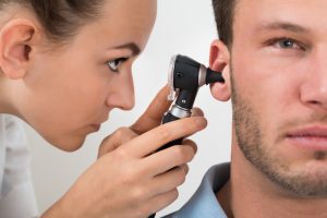 Physician Looking Into Male Patient's Ear With An Instrument